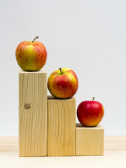 Wooden geometrical pieces with apples and light grey background