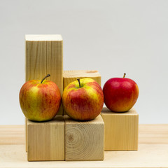 Wooden geometrical pieces with apples and light grey background