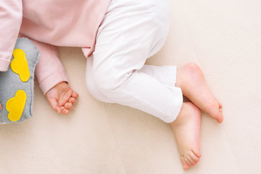 Adorable little close-up legs of baby toddler girl sleeping with an owl toy