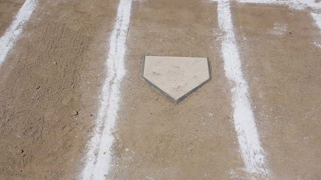 Horizontal pan of a baseball diamond's home plate and batters box chalk lines.
