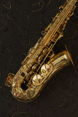 Fototapeta premium Golden saxophone and music sheets on a black background