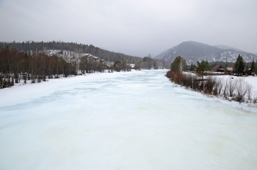 Icebound river on a cloudy spring day in the village