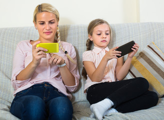 Woman and daughter with smartphones.
