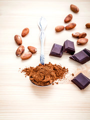 Brown chocolate powder in spoon , Roasted cocoa beans and dark c