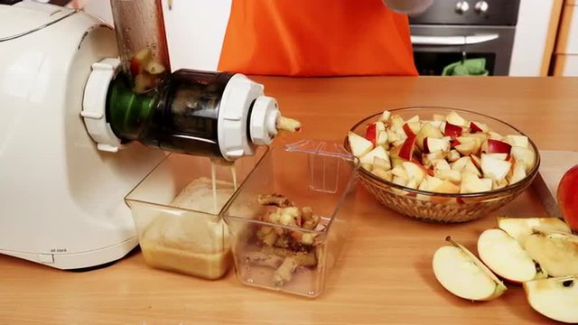 Female hands adding apple fruits in juicer machine 4K