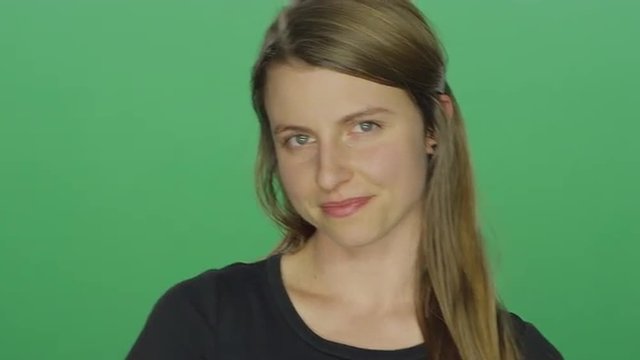 Young woman smiles, on a green screen studio background