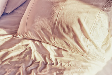 close up photo of pillow and sheets at morning sunrise in the bedroom. vintage filtered