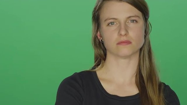 Young women looks upset and shakes her head, on a green screen studio background