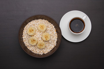 Woman hands holding spoon, healthy breakfast - eggs, black coffee and Oats flakes with banana. Whole grain cereal.
