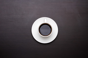 White cup of coffee on black table, top view