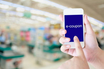 Hand holding mobile phone at supermarket checkout background, e