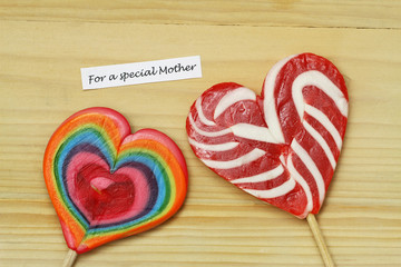 Happy Mother's day card with two colorful lollipops on wooden surface
