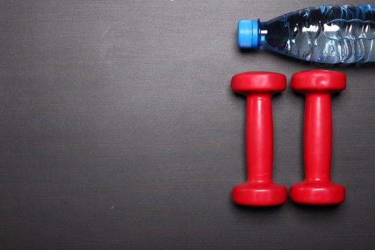 Fitness concept with dumbbells and bottle of water. Top view