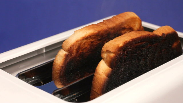 Slices of burnt toast pop up from an electric toaster.