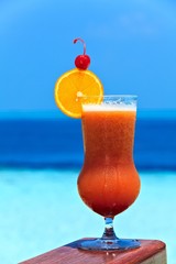 Obraz premium Glass of drink is on a beach table
