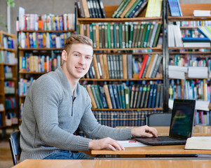 Portrait male student with laptop in the university library
