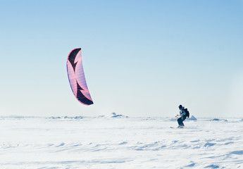 Kite surfer being pulled by his kite across the snow