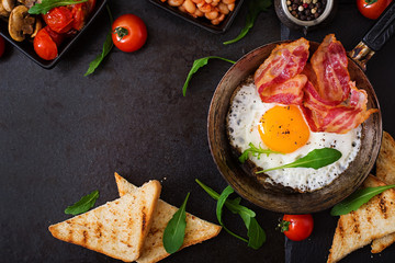 Engels ontbijt - gebakken ei, bonen, tomaten, champignons, spek en toast. Bovenaanzicht