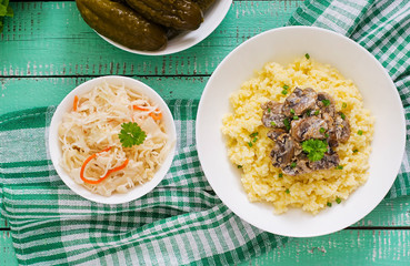 Millet porridge with mushrooms in a white bowl. Top view