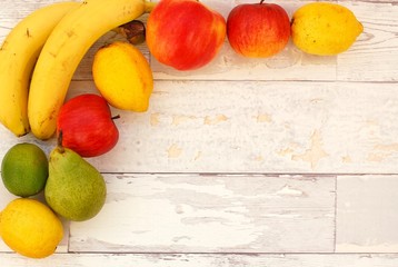 Banana, pear, lime, apples and lemons in the corner on the wooden background