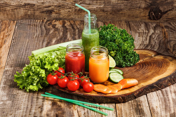 The bottles with fresh vegetable juices on wooden table