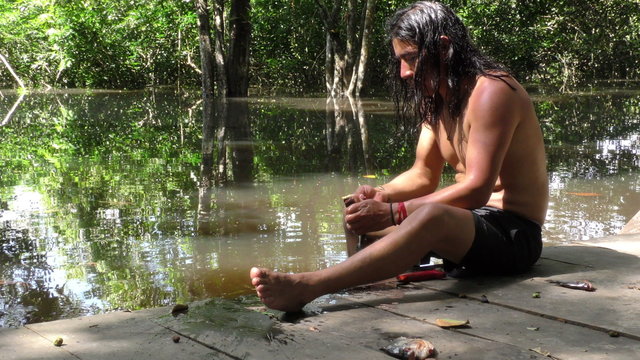 An indigenous man demonstrating traditional fish cleaning methods in the lush Amazonian jungle of Ecuador.