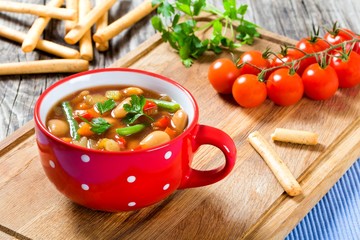Minestrone vegetable soup with beans, cauliflower, tomatoes, close-up, top view