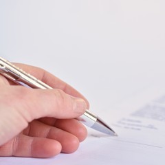 Hand with a pen when signing a document on paper.