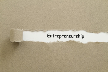 Entrepreneurship word written under torn paper.