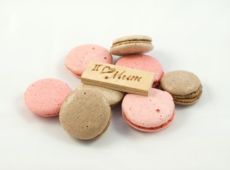 Chocolate and pink macarons chaotically arranged and a board with the inscription I love mum. A Happy Mother's Day theme