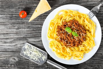 Bolognese ragout with italian pasta on a white plate, decorated with basil leaves, authentic...