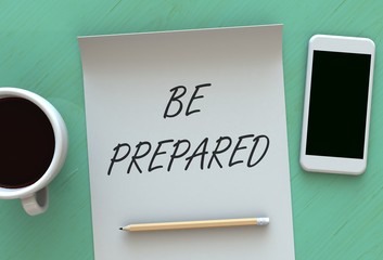 BE PREPARED, message on paper, smart phone and coffee on table