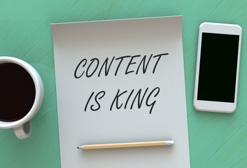 CONTENT IS KING, message on paper, smart phone and coffee on table