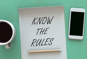 KNOW THE RULES, message on paper, smart phone and coffee on table