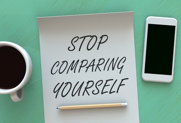STOP COMPARING YOURSELF, message on paper, smart phone and coffee on table