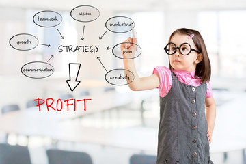 Cute little girl wearing business dress and writing a schema at the whiteboard with ideas for a...