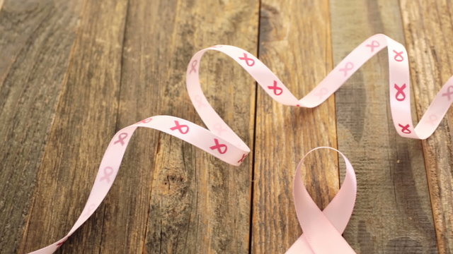Womens health symbol in pink ribbon on wooden board