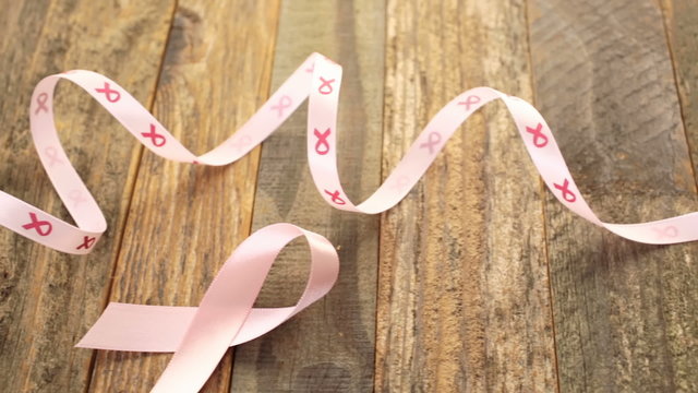 Womens health symbol in pink ribbon on wooden board
