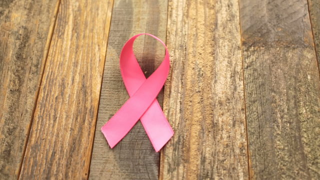 Womens health symbol in pink ribbon on wooden board