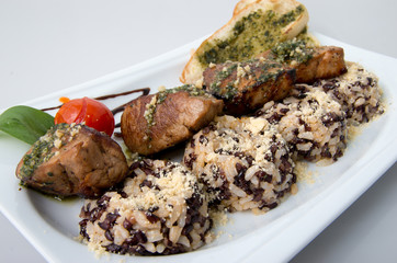 Bites of pork with white and black rice.