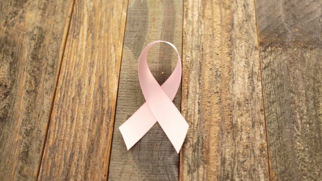 Womens health symbol in pink ribbon on wooden board