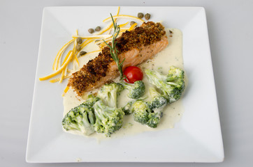 Fish breaded with nuts and broccoli in cream sauce.