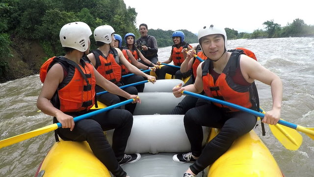 Experience the exhilaration of whitewater rafting as you join a group of joyful Asian individuals rowing at full speed,captured on an onboard camera with immersive sound.