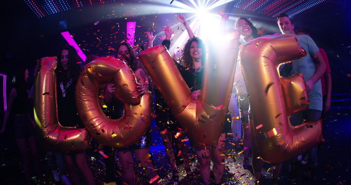 Festive young multi-ethnic crowd holding balloons saying love