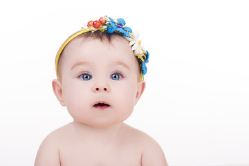 portrait of adorable little baby girl with headband with a decorative flowers. surprised baby child looking into the camera. lovely kid with big blue eyes. happy family concept