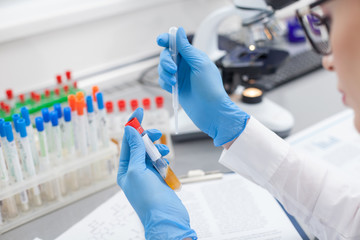 Cheerful female laboratory assistant working with flask