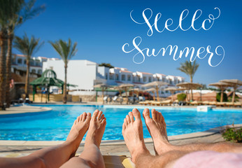 feet resting on a background of the pool and letters Hello Summer