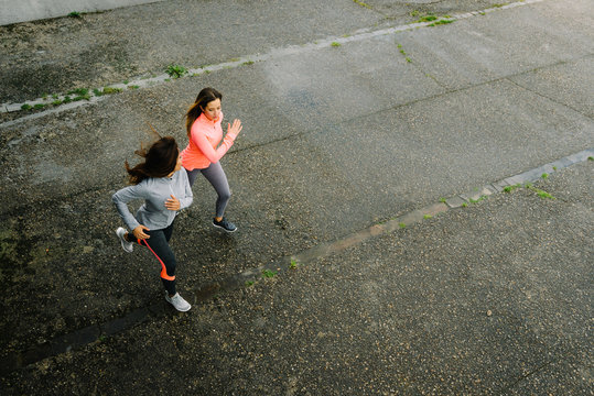 Top View Of Fitness Female Athletes Running On Rainy Day. Women Working Out Friends Training Together And Talking To Each Other.