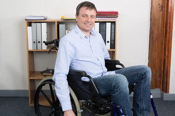 Handicapped Businessman sitting on wheelchair and using computer In Office