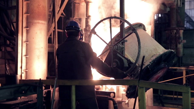 Worker on steel plant operates with  molten metal. HD.